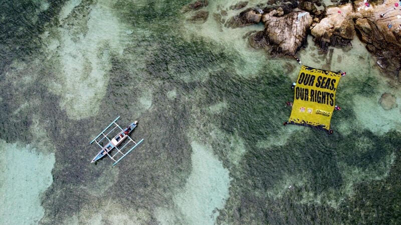 foto perhau diatas laut dengan spanduk selamatkan laut kita